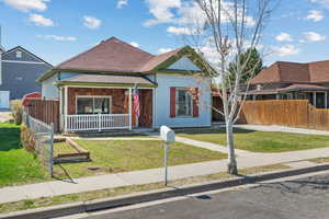 View of front facade with fence, a front lawn, and covered porch