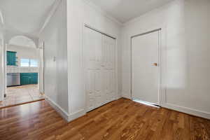 Entrance foyer with light wood finished floors, baseboards, and crown molding