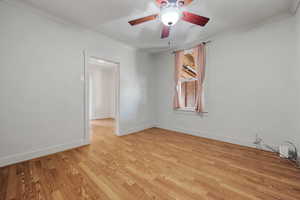 Spare room with light wood-type flooring, ceiling fan, crown molding, and baseboards