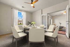 Dining room with visible vents, light colored carpet, baseboards, and ceiling fan