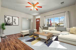 Living area with visible vents, baseboards, wood finished floors, and ceiling fan