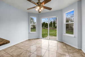 Unfurnished dining area featuring light tile patterned floors, baseboards, and ceiling fan