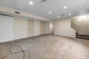 Finished basement featuring visible vents, baseboards, carpet, and stairs
