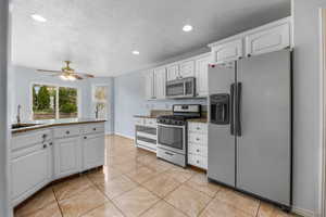 Kitchen with a sink, white cabinets, appliances with stainless steel finishes, and ceiling fan