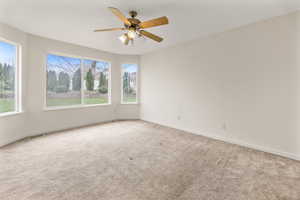 Carpeted empty room featuring baseboards, a ceiling fan, and visible vents