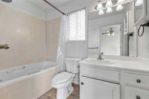 Full bathroom featuring shower / tub combo, vanity, tile patterned floors, toilet, and ceiling fan