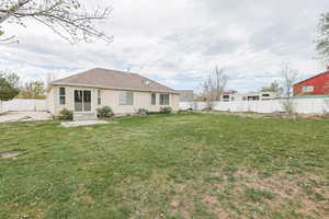 Back of property with stucco siding, central AC unit, entry steps, a fenced backyard, and a yard