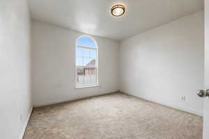 Carpeted spare room with visible vents and baseboards