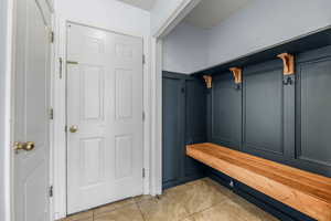 Mudroom with a decorative wall and light tile patterned flooring