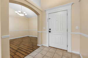 Foyer entrance featuring arched walkways, an inviting chandelier, baseboards, and light tile patterned floors