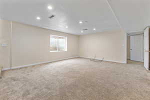 Empty room featuring visible vents, baseboards, recessed lighting, and light carpet