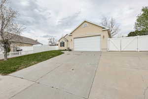 Exterior space featuring concrete driveway, stucco siding, a gate, a yard, and fence