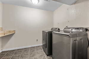 Clothes washing area with washer and dryer, visible vents, laundry area, and baseboards
