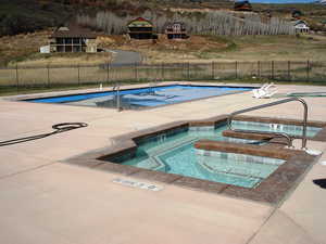 Pool featuring a patio area, fence, and a hot tub