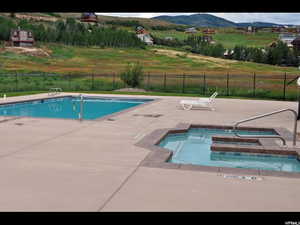 Community pool featuring a patio area, fence, a hot tub, and a mountain view