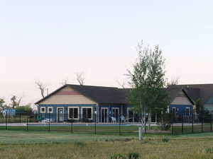 Back of clubhouse with a yard, a fenced in pool, and fence