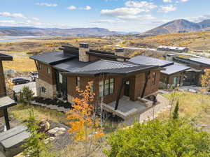 Back of property with a standing seam roof, a chimney, a metal roof, a mountain view, and a patio