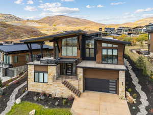 Contemporary house with a mountain view, concrete driveway, an attached garage, and stone siding
