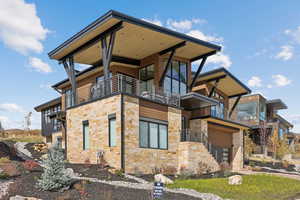 View of home's exterior featuring a balcony, stone siding, and stairs
