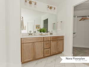 Full bath featuring marble finish floor, double vanity, a sink, and baseboards