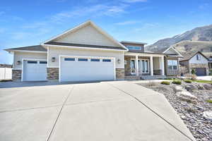 Craftsman house with an attached garage, driveway, and stone siding