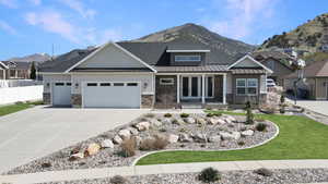 Craftsman-style home with a mountain view, an attached garage, stone siding, french doors, and driveway