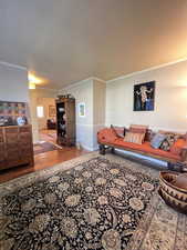 Living area with crown molding, wood finished floors, and baseboards