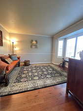 Living area with hardwood flooring, baseboards, ornamental molding, and a textured ceiling