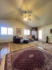 Living area featuring baseboards, a ceiling fan, hardwood floors, and vaulted ceiling.