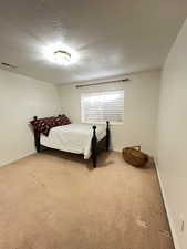 Carpeted bedroom with a textured ceiling, baseboards, and visible vents