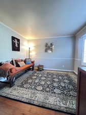 Living area featuring baseboards, a textured ceiling, and ornamental molding