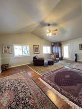 Living room featuring baseboards, a ceiling fan, vaulted ceiling, and wood finished floors