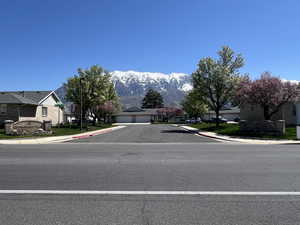 View of road with curbs, a residential view, a mountain view, and sidewalks