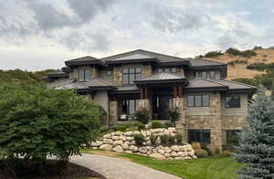 Prairie-style house featuring stone siding, a standing seam roof, a metal roof, and a front lawn
