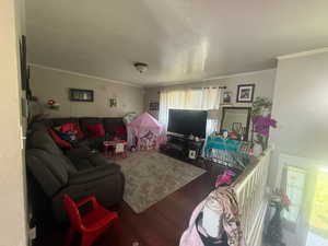 Living area with crown molding and wood finished floors