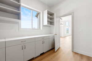 Kitchen with baseboards, open shelves, light countertops, a chandelier, and light wood-style flooring