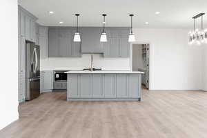 Kitchen featuring gray cabinetry, baseboards, light countertops, and stainless steel fridge