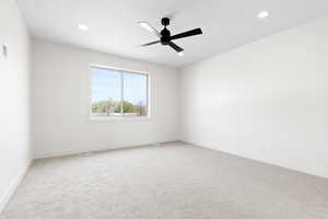 Empty room featuring light carpet, ceiling fan, baseboards, and recessed lighting