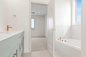 Full bath featuring tile patterned floors, plenty of natural light, vanity, and a garden tub