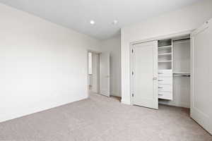 Unfurnished bedroom with a closet, recessed lighting, light colored carpet, and baseboards