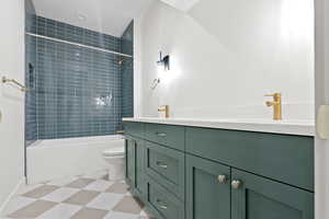 Full bath featuring toilet, double vanity, tub / shower combination, and a sink