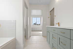 Full bath with vanity, baseboards, tile patterned flooring, visible vents, and tiled tub
