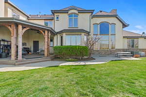 Back of property with ceiling fan, stucco siding, a lawn, a patio area, and stone siding
