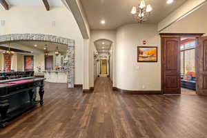 Foyer with dark wood-type flooring, arched walkways, an inviting chandelier, and recessed lighting