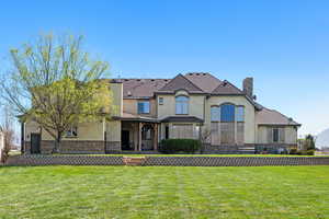 View of front facade with stucco siding, a chimney, and a front lawn