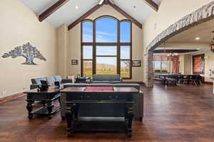 Game room featuring baseboards, an inviting chandelier, beam ceiling, wood finished floors, and high vaulted ceiling
