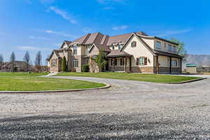 View of front facade featuring curved driveway, stucco siding, stone siding, and a front yard