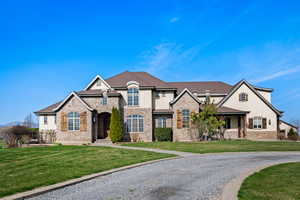 French country inspired facade featuring a front yard, brick siding, stucco siding, and stone siding