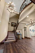 Stairs featuring baseboards, a chandelier, recessed lighting, arched walkways, and wood finished floors