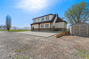 View of front facade featuring a mountain view, a shed, a chimney, an outdoor structure, and stucco siding